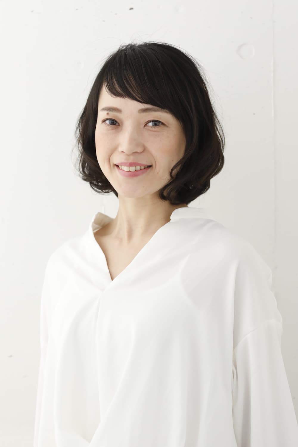 パーマのあるボブスタイルの女性（正面）