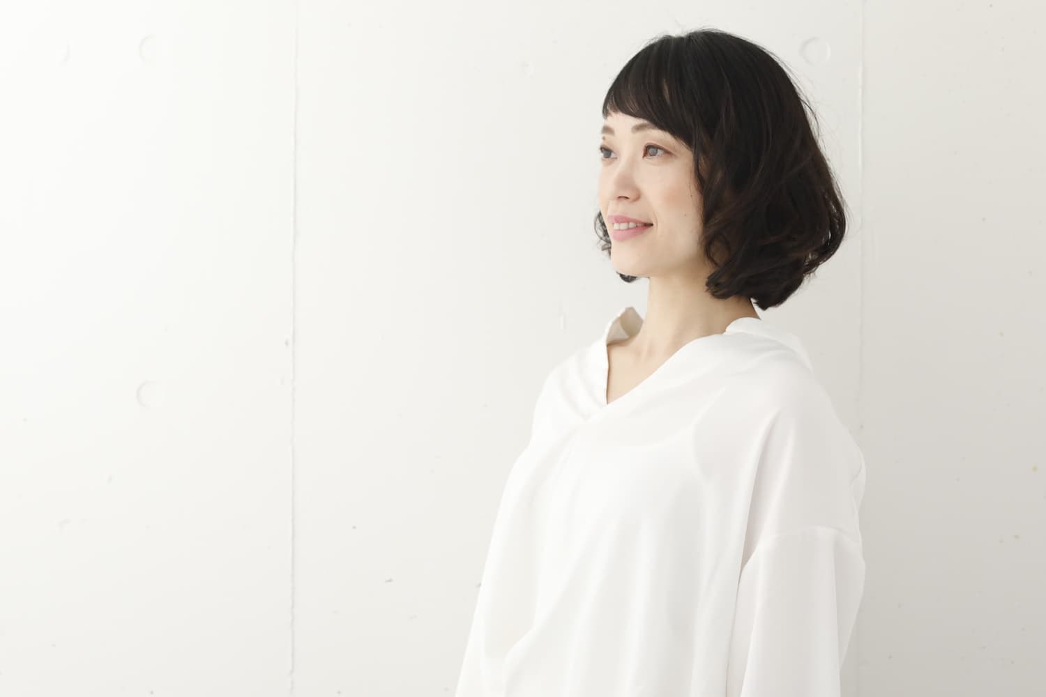 パーマのあるボブスタイルの女性（斜め横）