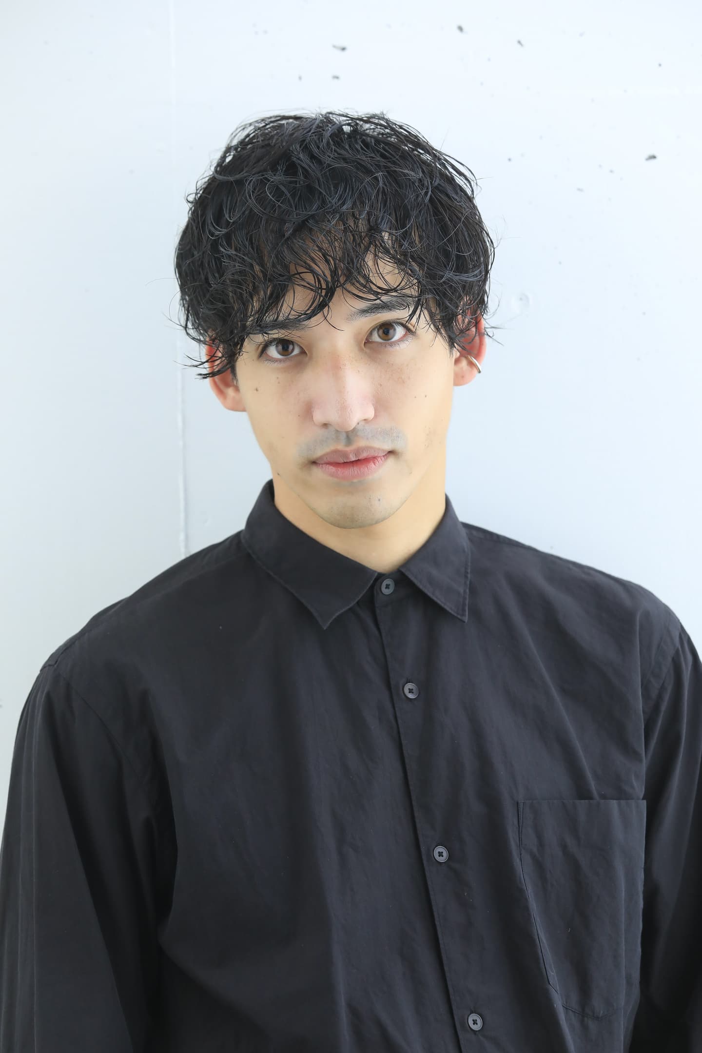 強めパーマでウェットスタイルの男性