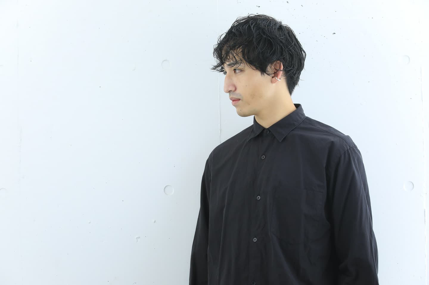 横を向いている強めパーマスタイルの男性